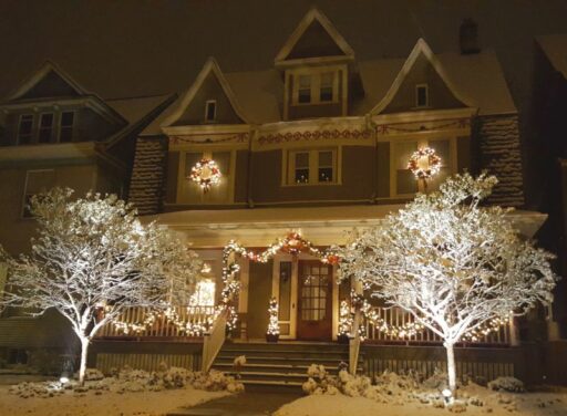 Victorian home decorated in lighted garlands, wreaths and trees
