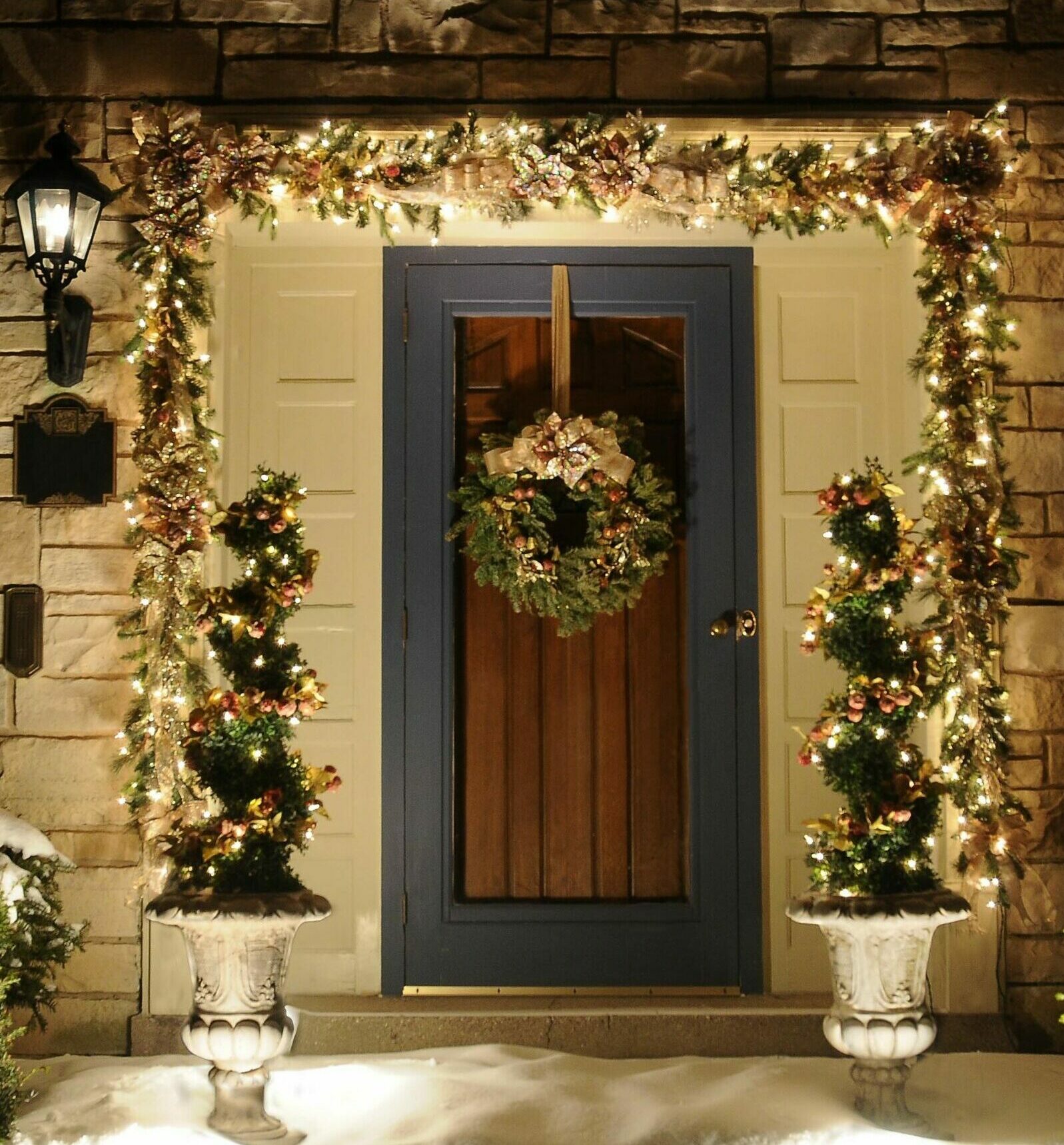 Exterior custom-crafted holiday garland, wreath and spiral topiary create an elegant evening Christmas look for a Wauwatosa, WI Colonial home.